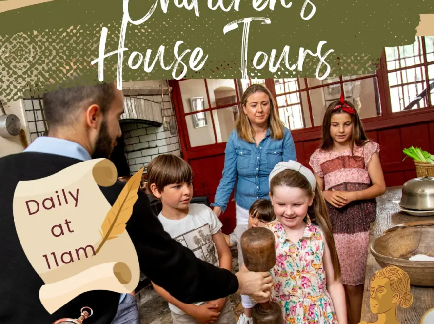 A group of children and an adult guide gather in a historical kitchen. A girl holds a wooden tool, while a scroll reads "Daily at 11am." The text above says "Children’s House Tours.